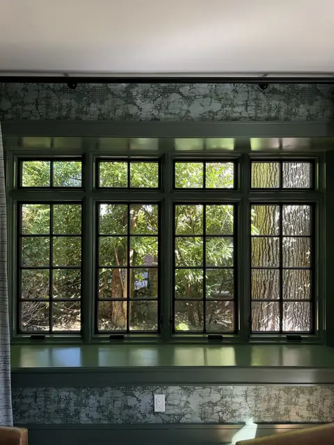 Window wall with deep green trim in a wallpapered sitting room