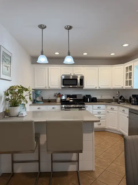 White kitchen cabinets around an island with pendant lights