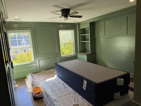 Bedroom with green paneled walls and built-ins