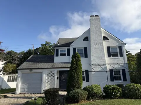 Front of a century-old Manhasset home painted white with black shutters