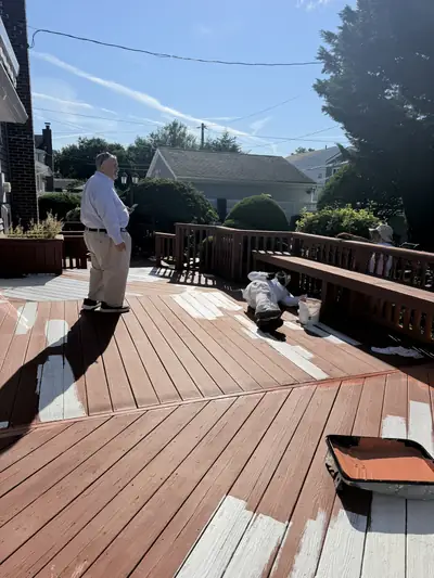 Crew member rolling stain onto deck boards outdoors