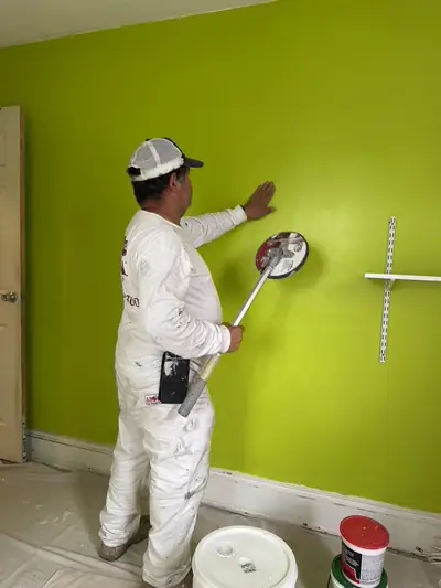 Painter rolling a bold green color onto a wall