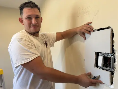 Painter patching drywall before painting