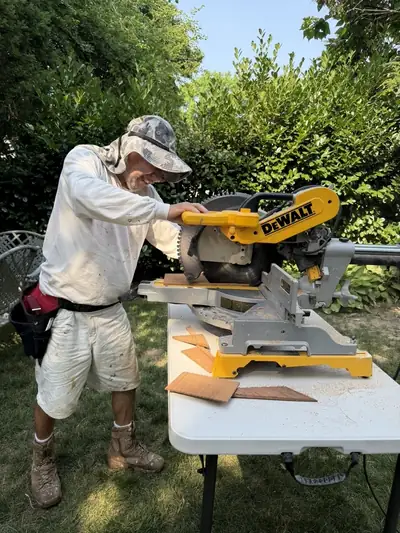 Crew member cutting trim on a miter saw in the backyard