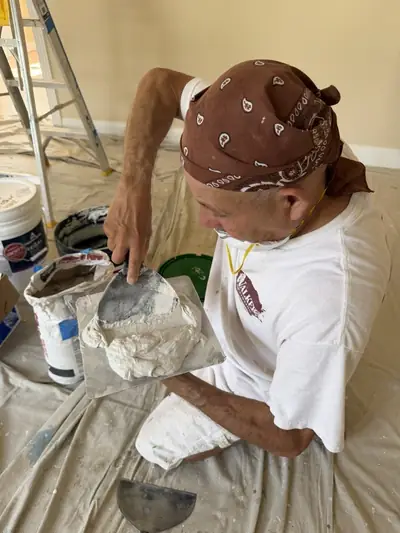 Painter skim-coating a wall with a trowel of joint compound