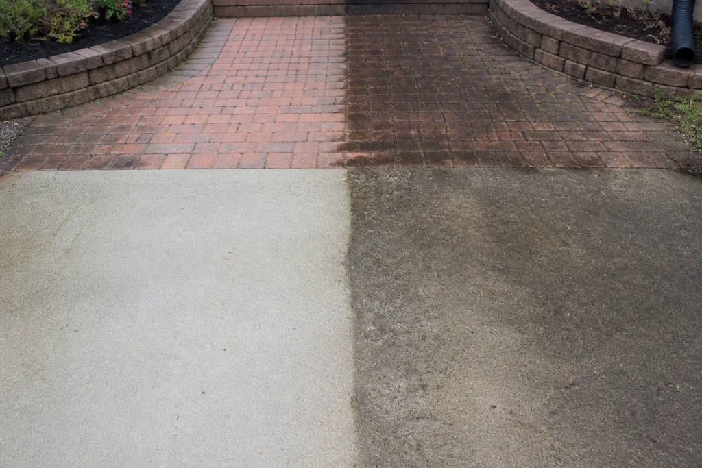 Brick pavers and a concrete walkway cleaned in a clear stripe, the left half bright and the right half still dark with dirt and grime, washing results