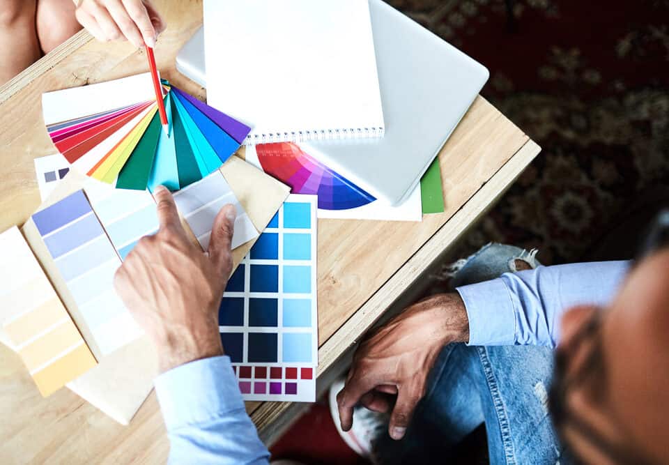 gentleman pointing to a sky blue color on a wide selection of colored papers and palettes. Color Consulting
